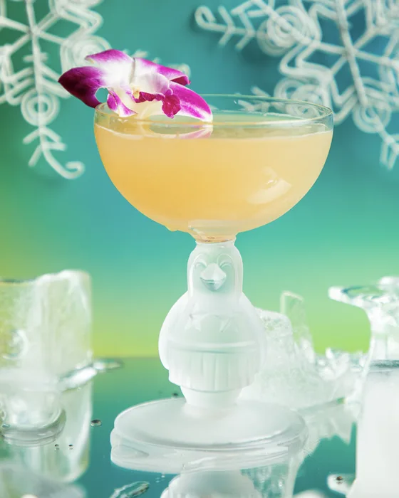 Pau Hana Penguin cocktail in a frosted penguin coupe with an orchid garnish