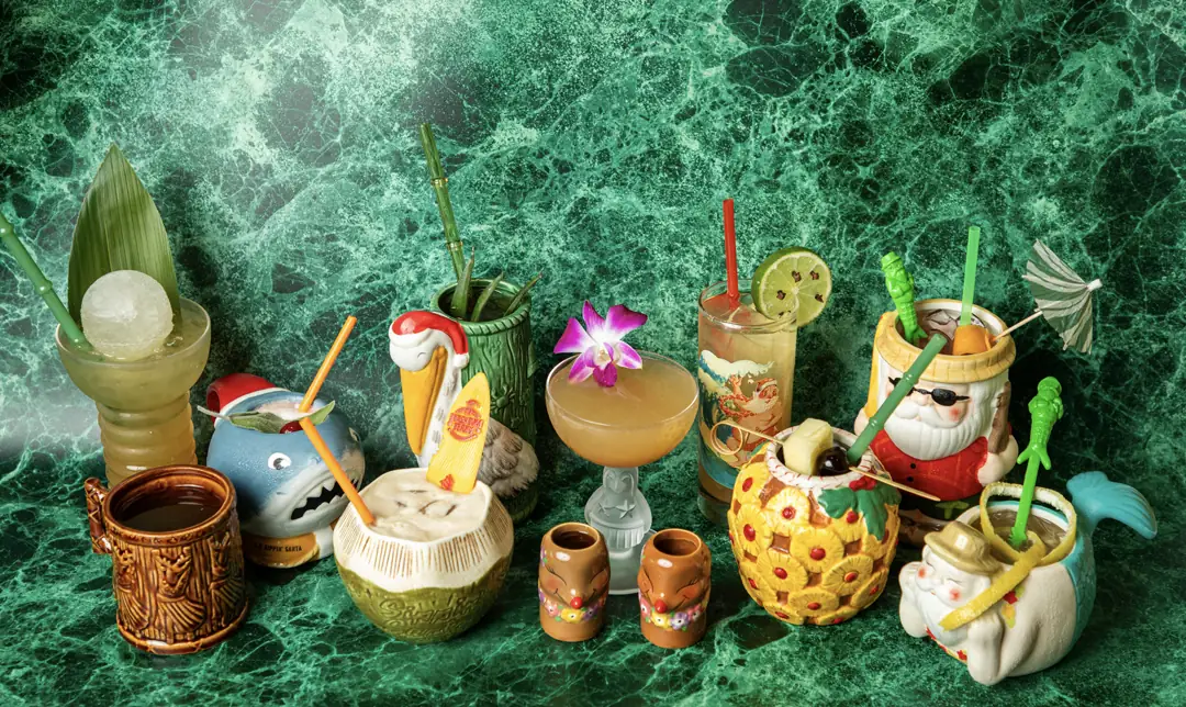 The full Sippin' Santa 2026 lineup of custom tiki mugs and glassware on green marble